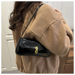 Détail d'un sac baguette en cuir verni noir brillant avec un fermoir en métal doré