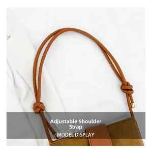 Detail of adjustable knotted shoulder strap with gold metal tips on brown bucket bag
