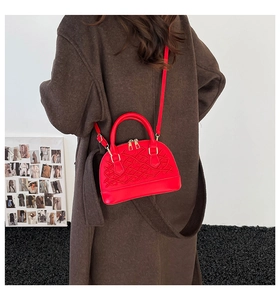 Makro-Detail der roten gesteppten Muscheltasche mit Goldbeschlägen und Sticknähten