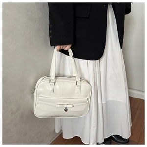 Detail of white glossy leather Boston bag with bow decoration and heart charm
