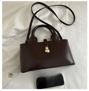 Detailed view of dark brown faux leather bag with a unique gold spherical pendant