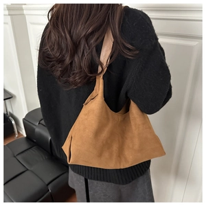 Detailansicht der braunen Wildleder-Hobo-Tasche, getragen von einem Modell in Minimalismus