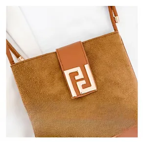 Macro detail of brown suede handbag featuring a refined gold F-shaped metal buckle