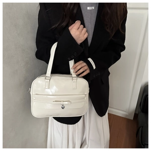 Detail of white patent leather handbag with bow decoration and silver heart charm