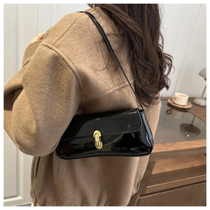 Detail of glossy black patent leather shoulder bag with vintage gold buckle closure