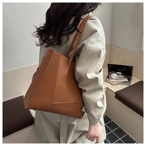 Macro detail of brown leather tote bag with geometric V-shaped stitching and shoulder straps
