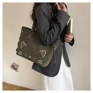 Detail of dark green canvas tote bag with cat graphic and brown leather handles