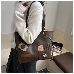 Vista detallada del bolso tote de cuero marrón vintage con parches usado por una modelo