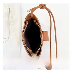 Detail view of the brown leather bucket bag interior with purple lining and gold zipper