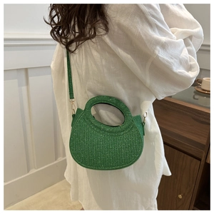 Detail of emerald green sequin handbag shown on shoulder in a minimalist indoor setting