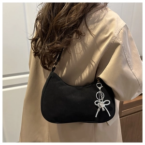 Detail of a black hobo bag featuring a silver beaded bow charm with a heart centerpiece