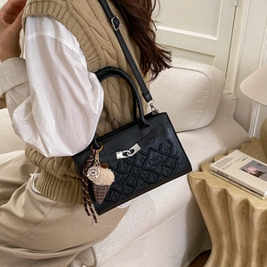 Chic black woven textured crossbody bag with ice cream charm on a cozy sofa setting