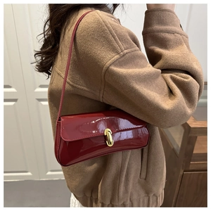 Macro shot of dark red patent leather texture and vintage gold buckle on shoulder bag
