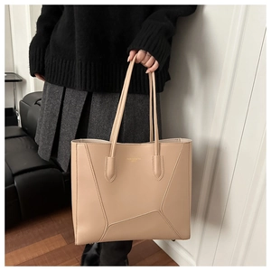 Detailed close-up of beige tote bag with geometric stitching and slim shoulder straps