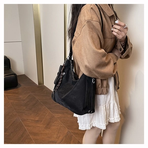 Vue détaillée d'un grand sac seau en cuir noir porté à l'épaule par un mannequin