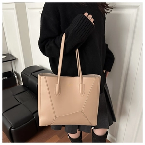 Close-up of beige leather tote bag with geometric stitching and gold logo details
