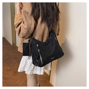 Detalle del bolso de hombro de nailon negro con borlas plateadas llevado por la modelo