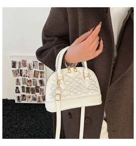 Detail der weißen PU-Leder-Schalen-Tasche mit geometrischer Stickerei und Gold-Hardware am Model
