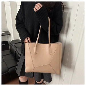 Detail of beige large tote bag featuring geometric stitching and gold letter embossing