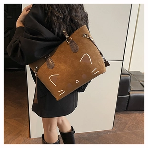 Detail of vintage brown tote bag with minimalist cat pattern and decorative side tassel