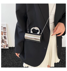 Detail of silver metallic cylinder bag with wavy handle and chain strap on a model