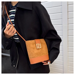 Detail shot of brown suede bucket bag with gold geometric logo and leather shoulder strap