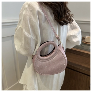 Pink sequined crescent bag with cutout handle and shoulder strap shown in a lifestyle setting