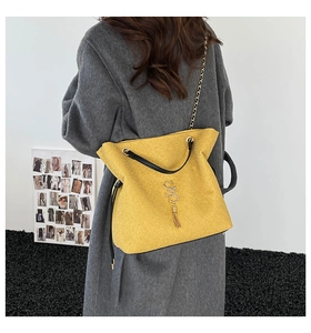 Détail du sac cabas jaune scintillant avec poignées noires et pendentif à franges dorées