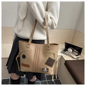 Side view of khaki oversized tote bag with retro patches on a shoulder-carried model