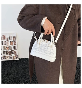 Detail of white shell bag with 3D geometric texture and golden zipper on wool coat