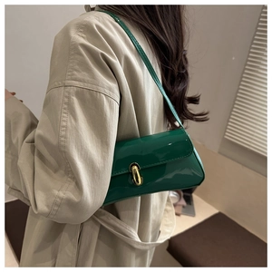 Detail of dark green glossy patent leather shoulder bag with gold metal buckle