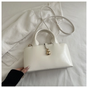 Detail of white PU leather handbag with golden gourd pendant on corduroy texture