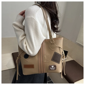 Detailed side view of khaki leather tote bag with patchwork and drawstring features