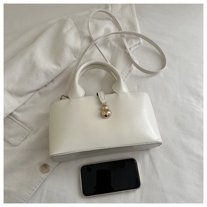 Detail of white PU bucket bag with golden gourd buckle on striped blazer background