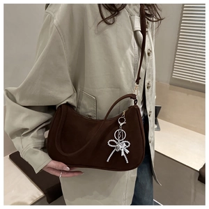 Détail du sac demi-lune marron foncé mat avec pendentif élégant en forme de nœud