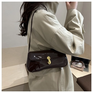 Detail of burgundy baguette bag with sleek patent finish and golden buckle on shoulder