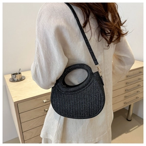 Sac à main demi-lune noir pailleté porté en bandoulière par un mannequin de mode