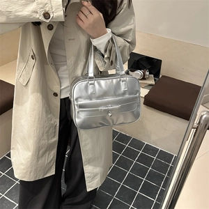 Silver metallic shoulder bag with bow stitching and heart pendant in a chic urban style