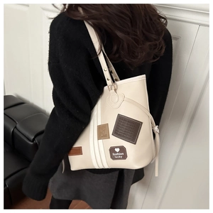 Detail of cream tote bag with heart patch and drawstring tassels shown on person