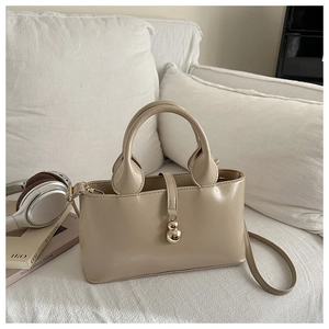 Dettaglio borsa a mano beige con ciondolo a forma di zucca dorata e tracolla