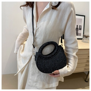 Detail of black glitter crescent handbag featuring circular cutout handle and slim strap