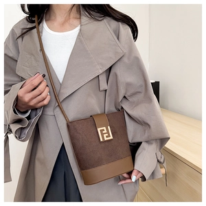 Detail of a brown bucket bag with suede texture and a golden geometric buckle close-up