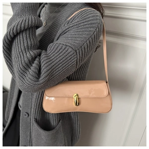 Detail of a minimalist patent leather shoulder bag with a gold cylindrical rotary lock