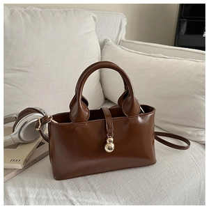 Borsa in ecopelle marrone con ciondolo in metallo su un divano alla moda