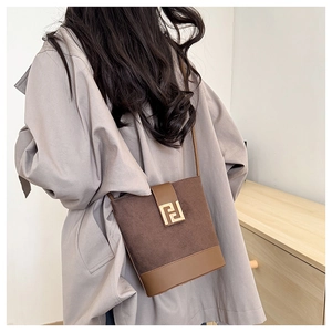 Detail of brown contrast leather bucket bag with gold geometric metal buckle and strap