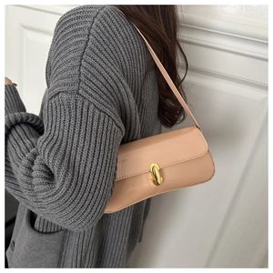 Detail of glossy apricot baguette bag featuring a gold rectangular buckle and slim strap