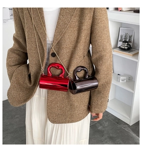 Nahaufnahme einer zylindrischen Mini-Tasche mit herzförmigem Griff und feiner Metallkette