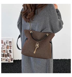 Close-up of dark brown tweed tote bag featuring gold interlocking logo and chain strap