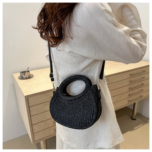 Détail du sac à main noir scintillant avec poignée ronde et boucles dorées sur modèle