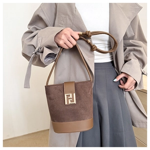 Detail of a two-tone suede bucket bag featuring a gold geometric clasp and knotted leather strap